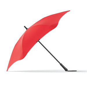 A red Blunt Classic umbrella with a fabric handle strap, displayed in an open position against a white background.